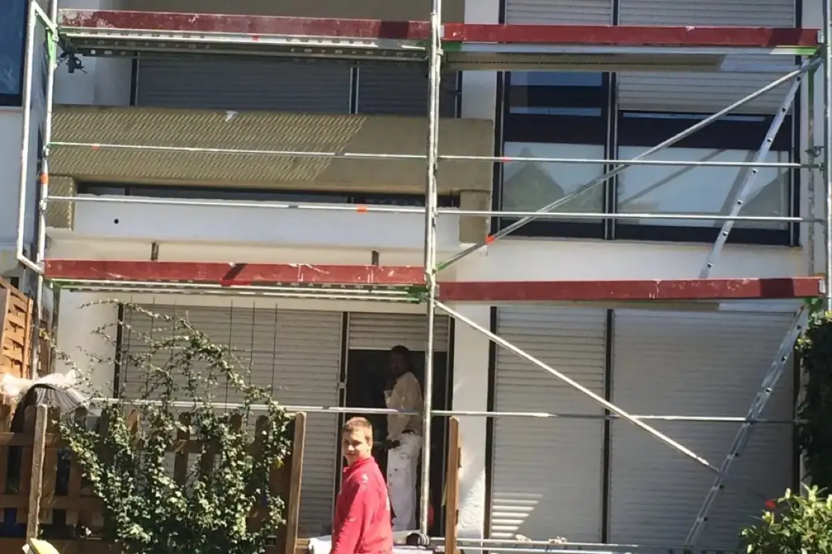 Fassadenanstrich Reihenhaus Karben — Geruest, Andymen-Maler in roter Jacke