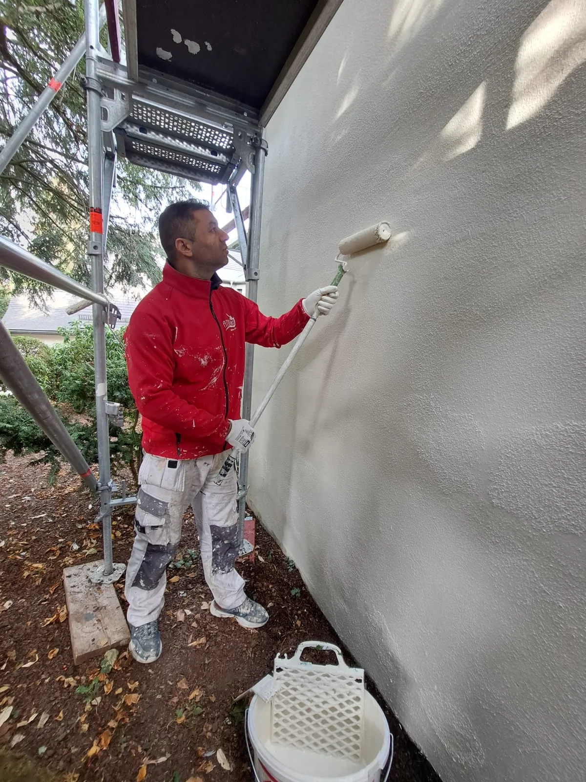 Maler streicht Fassade — Alternative zur Fassadenverkleidung