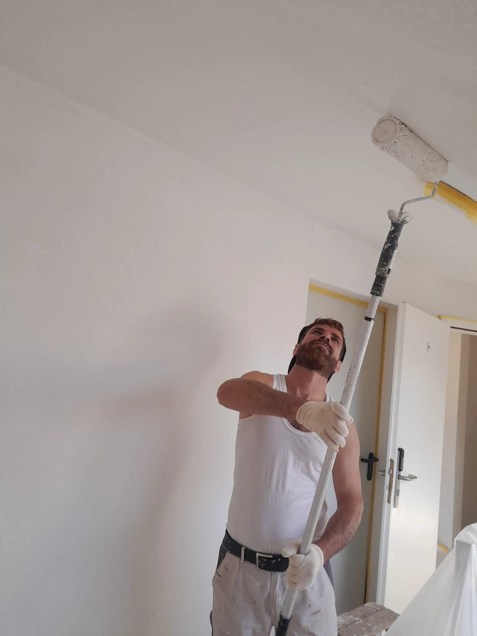 Maler streicht Decke mit Verlaengerungsstange in Dachgeschosswohnung Hochheim
