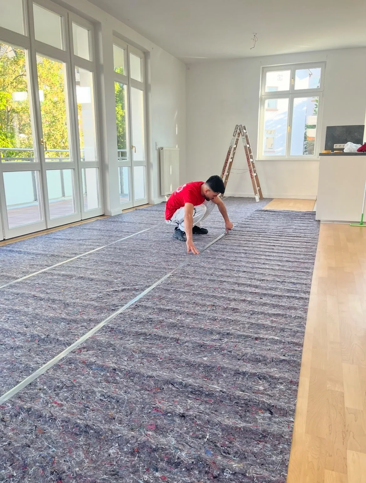 Maler legt Malervlies im grossen Wohnraum mit Balkon in Marburg aus