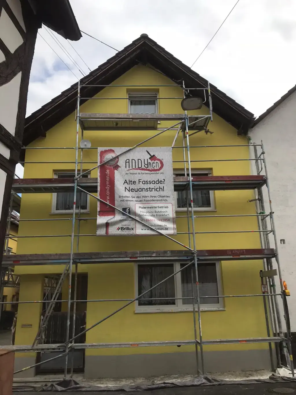 Altbau Reihenhaus Florstadt nachher — frisch gestrichen in Gelb mit Andymen-Banner