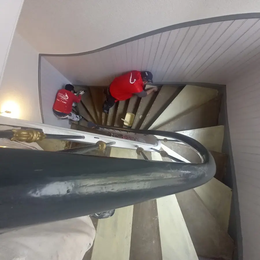 Treppenhausrenovierung Wetterau &mdash; Andymen Team bei der Arbeit, rote Jacken, Wendeltreppe