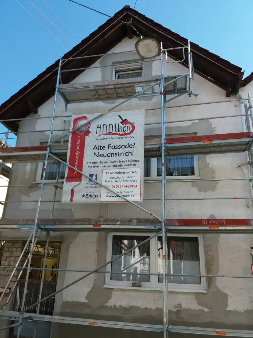 Altbau Reihenhaus Fassade vorher — Geruest mit Andymen-Banner, Putzschaeden sichtbar