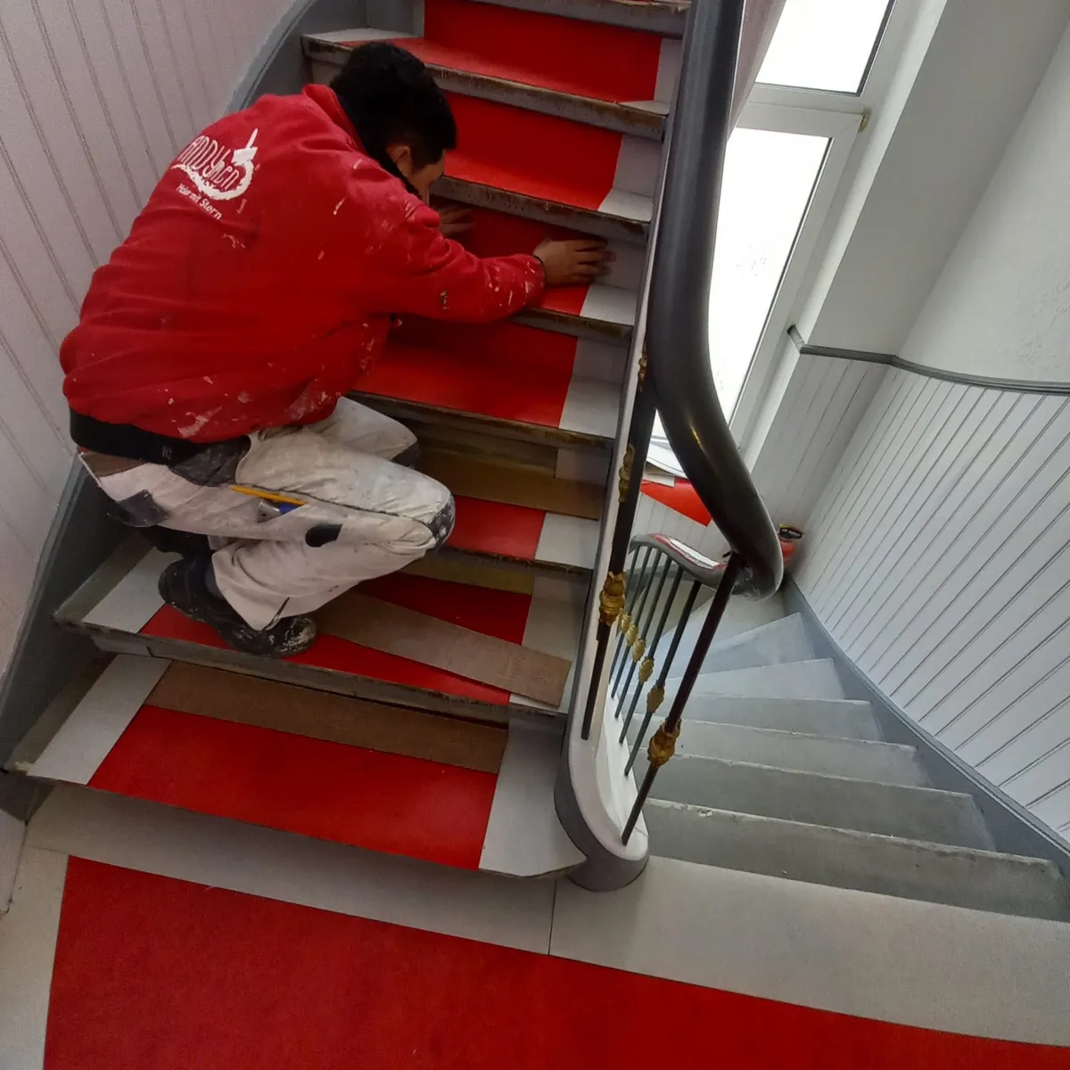 Andymen Mitarbeiter rote Jacke klebt Treppe ab