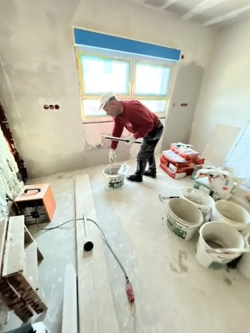 Andymen-Maler spachtelt in Altbau mit offenen Leitungen