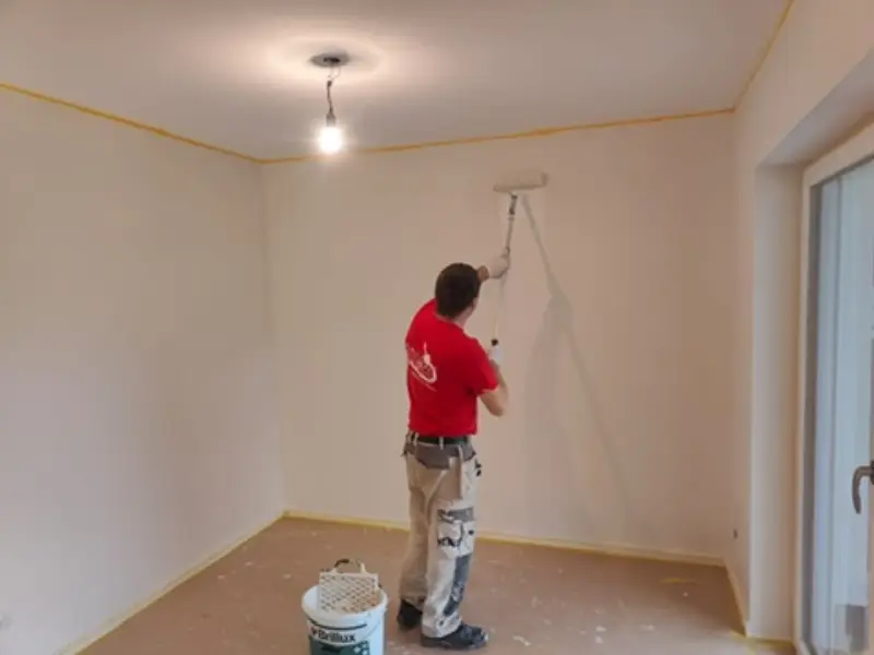 Andymen-Maler streicht Decke mit Teleskoprolle