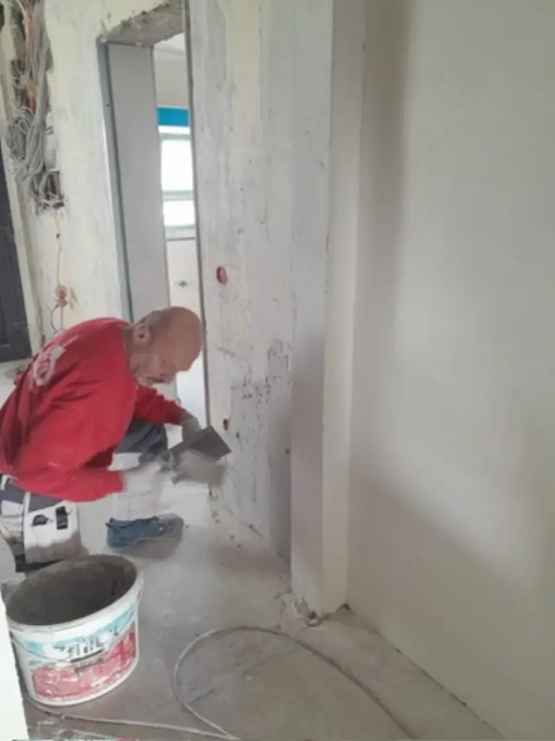 Andymen-Maler spachtelt Wand mit Kelle